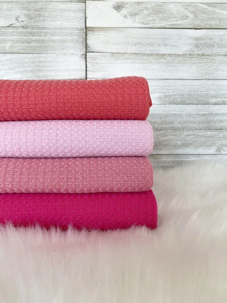 May include: Four waffle weave fabric swatches stacked on top of each other. The swatches are in shades of pink, coral, and red.