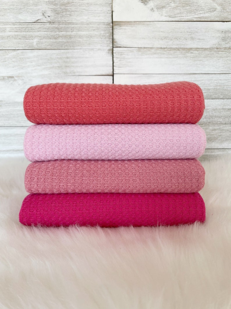 May include: Stack of four waffle weave fabric swatches in shades of pink, coral, and fuchsia.
