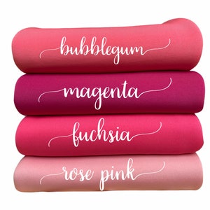 May include: A stack of four fabric rolls in shades of pink and red. The colors are bubblegum, magenta, fuchsia, and rose pink. Each roll has a white cursive label with the color name.