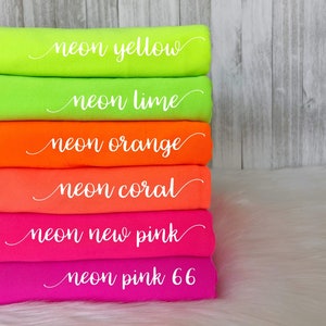 May include: Stack of six fabric rolls in neon colors. The rolls are labeled "neon yellow", "neon lime", "neon orange", "neon coral", "neon new pink", and "neon pink 66".