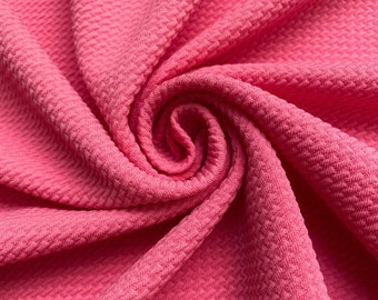 May include: Pink textured fabric with a waffle-like pattern. The fabric is folded and twisted, creating a swirling effect.