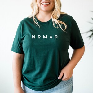 May include: A dark green t-shirt with the word "NOMAD" printed in white on the front.