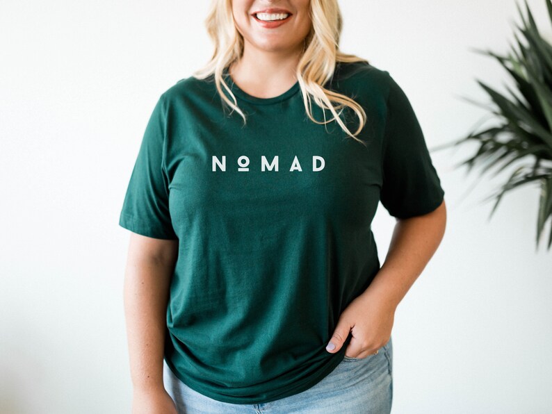 May include: A dark green t-shirt with the word "NOMAD" printed in white on the front.