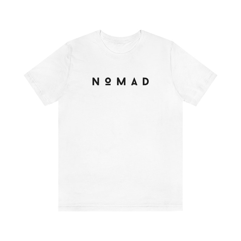 May include: White t-shirt with black text that reads "NOMAD"