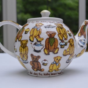 May include: White teapot with a brown and yellow teddy bear design. The teapot has a lid and a spout. The text "It's the day the teddy bears have tea" is printed on the bottom of the teapot.