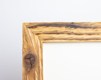 Könnte beinhalten: Ein rustikaler Holzrahmen mit natürlicher Holzoptik. Der Rahmen hat einen Knoten im Holz und einen weißen Hintergrund.