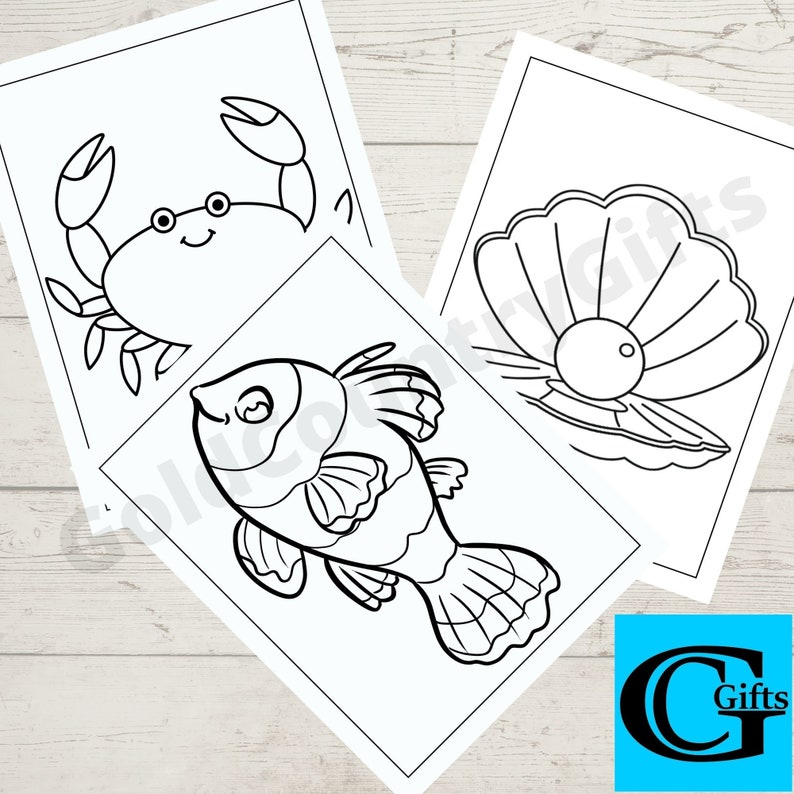 May include: Three black and white colouring pages featuring a crab, a fish, and a pearl inside a clam shell. The pages are on a white wooden background.