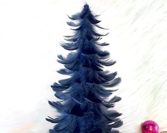 May include: A dark blue feather Christmas tree with a variety of colorful ornaments around the base.
