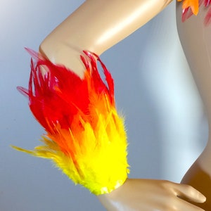 May include: Red, orange, and yellow feather armband. The feathers are arranged in a gradient pattern, creating a flame-like effect.