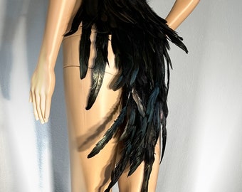 May include: Black feather skirt with a long train. The skirt is made of black feathers and has a waistband.