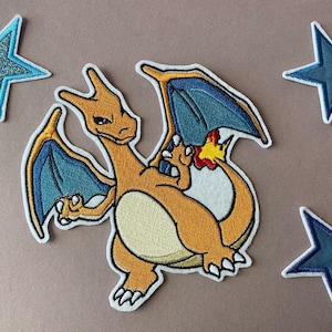 Könnte beinhalten: Gestickter Aufnäher mit einem Charizard-Design in Orange, Blau und Gelb, umgeben von vier sternförmigen Aufnähern. Die Aufnäher haben einen weißen Rand und sind vor einem neutralen Hintergrund platziert. Ideal für Jacken, Taschen oder andere Stoffartikel.
