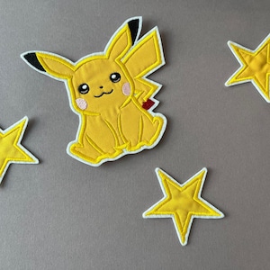Könnte beinhalten: Gelbe gestickte Bügelbilder mit einem Pikachu-Cartoon und drei Sternen.