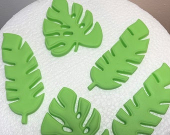 May include: Five green leaf-shaped cake toppers, two are monstera leaves and three are palm leaves. The leaves are made of fondant and are perfect for decorating cakes and cupcakes.