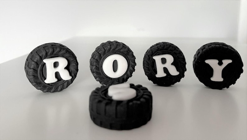 a collection of black tire-shaped cookies arranged to spell out the word "RORY".