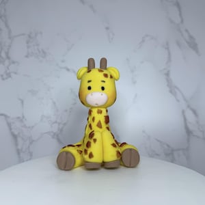 A yellow and brown giraffe figurine is sitting on a white surface against a marble background.