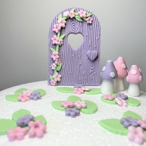 May include: Purple and green fairy door cake topper with pink and purple mushrooms and flowers.