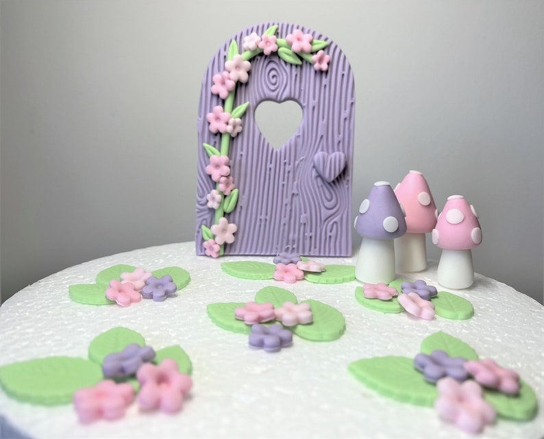 May include: Purple and green fairy door cake topper with pink and purple mushrooms and flowers.