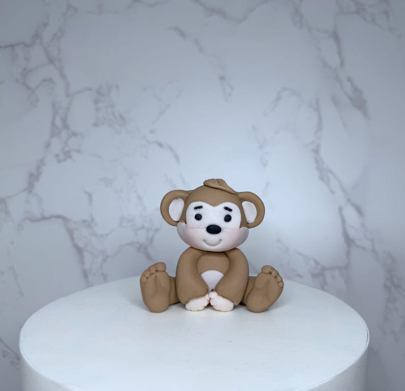 A small brown monkey figurine sitting on a white cake.