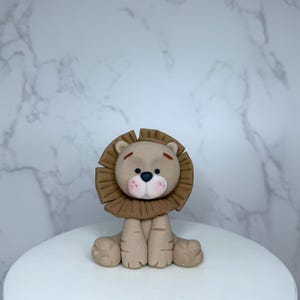 A brown lion figurine is sitting on a white surface against a marble background.
