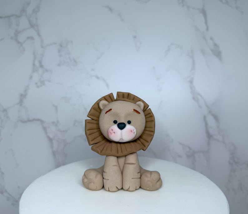 A brown lion figurine is sitting on a white surface against a marble background.