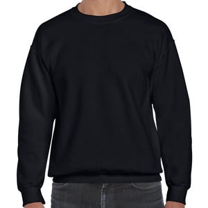 May include: A solid black crew neck sweatshirt. The long-sleeved top has a ribbed hem and cuffs. The sweatshirt is made of a soft material and is suitable for casual wear. The model is wearing dark gray jeans.