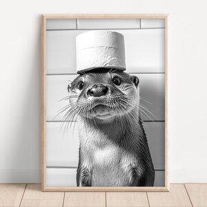 May include: A black and white photo of an otter wearing a toilet paper roll as a hat. The otter is looking directly at the camera.