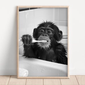 May include: A black and white photograph of a chimpanzee brushing its teeth in a bathtub. The chimpanzee is holding a toothbrush in its right hand and is looking at the camera.