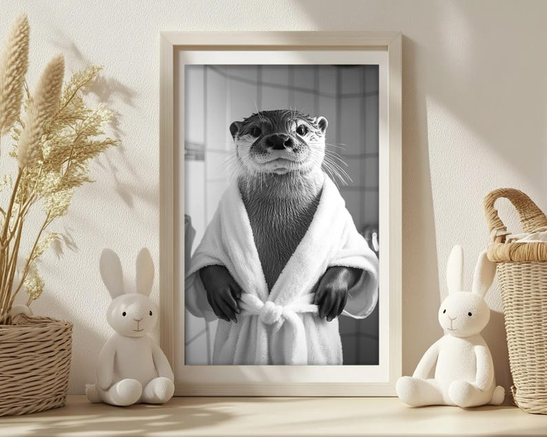 May include: A black and white photo of an otter wearing a white bathrobe. The otter is looking directly at the camera with a serious expression. The photo is framed in a white frame.