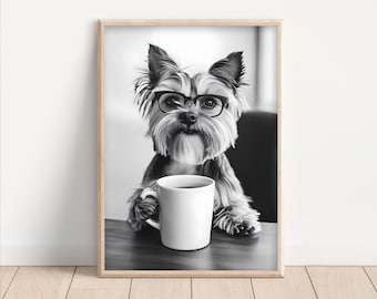 May include: A black and white photograph of a dog wearing glasses and holding a white coffee mug. The dog is sitting at a wooden table.