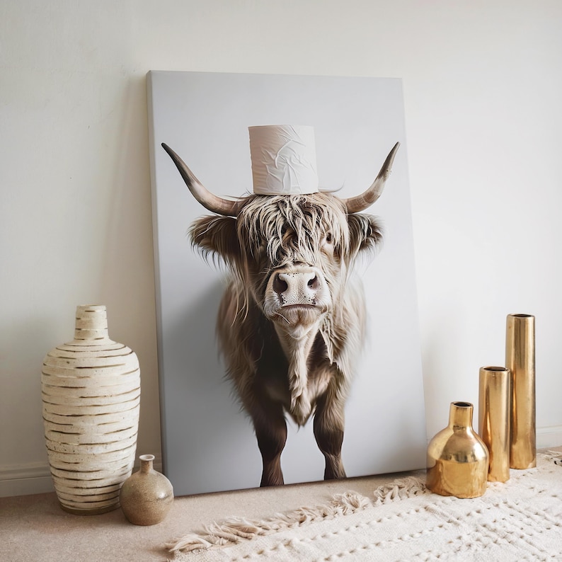 May include: A canvas print featuring a Highland cow with a roll of toilet paper balanced on its head. The cow has long, shaggy brown fur and large horns. The print is displayed against a white background, with decorative vases in the foreground.