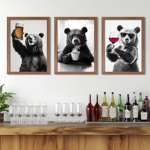 Pode incluir: Três impressões emolduradas em preto e branco de ursos a desfrutar de bebidas. O urso à esquerda segura um copo de cerveja, o urso do meio segura uma chávena de café e o urso à direita segura um copo de vinho.