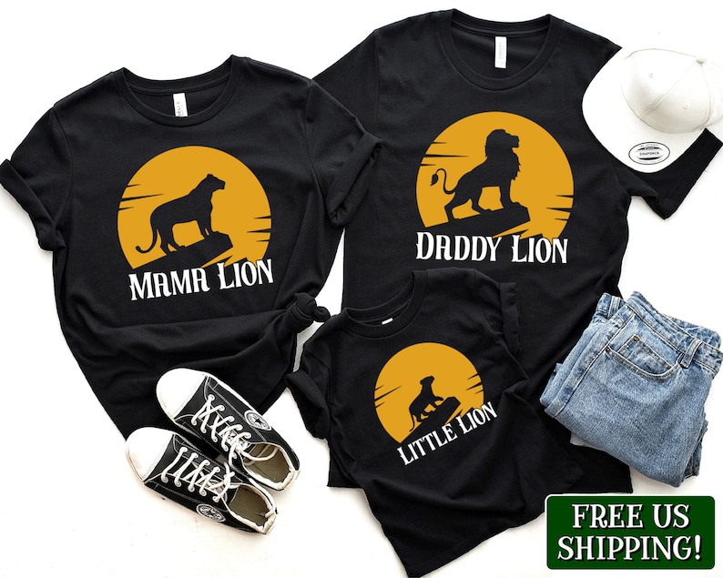 May include: A set of three black t-shirts with a lion silhouette and a yellow sun graphic. The shirts read "Mama Lion", "Daddy Lion", and "Little Lion".