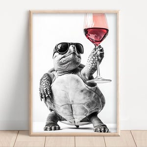 May include: Framed black and white print featuring a turtle wearing sunglasses, raising a glass of red wine. The image has a humorous tone, with the turtle depicted in a relaxed pose. The background is plain white, enhancing the subject.