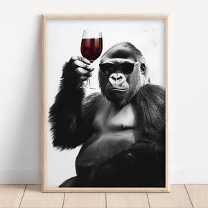 May include: Black and white framed print of a gorilla wearing sunglasses, holding a glass of red wine. The image has a humorous and sophisticated theme, suitable for home decor.