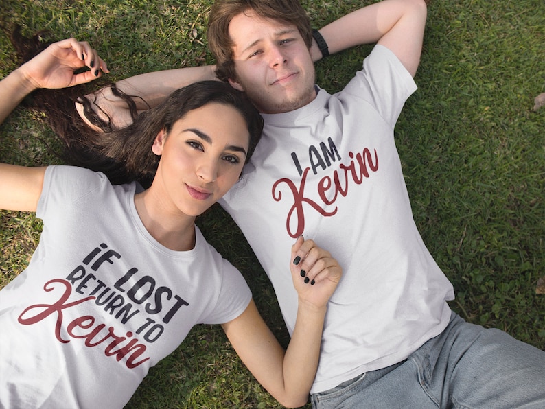 May include: A couple wearing white t-shirts with a red graphic design. The woman's shirt says "If lost return to Kevin" and the man's shirt says "I am Kevin".