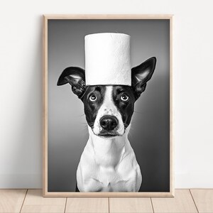 May include: Black and white photograph of a dog with a roll of white toilet paper balanced on its head. The dog has black and white markings and is looking directly at the camera. The image is framed in a wooden frame.
