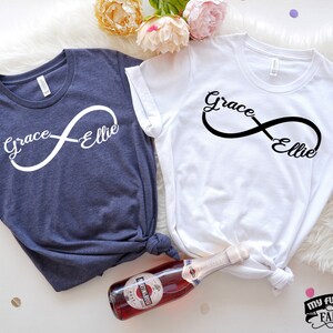 May include: Two t-shirts with an infinity symbol and the names "Grace" and "Ellie" on each side. The shirts are navy blue and white.