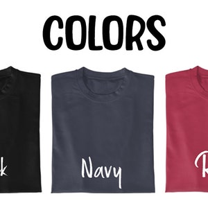 May include: Three folded t-shirts in black, navy blue, and red with the word "Black", "Navy", and "Red" written in white on each shirt. The word "COLORS" is written in black above the shirts.