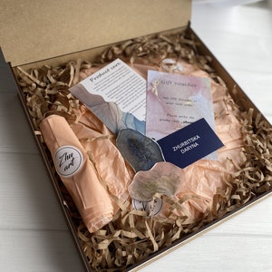 May include: A gift box filled with brown packing paper and a peach-colored tissue paper. The box contains two resin art pieces, a gift voucher with the text "Get 10% discount on your next order. Please write me promo code: zhug", and a business card with the text "ZHURBITSKA DARYNA".