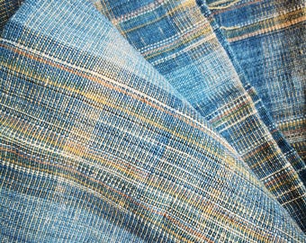 May include: Close-up of a blue and yellow woven fabric with a textured pattern. The fabric is folded and shows the intricate details of the weave.