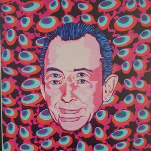 May include: A colorful pop art print featuring a portrait of a man with multiple eyes. The background is a pattern of pink, orange, and blue oval shapes. The artwork is framed in black and is displayed on a green surface.