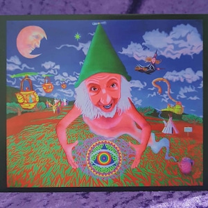 Puede incluir: Una pintura surrealista y colorida que presenta una figura parecida a un gnomo con un sombrero verde y barba blanca, sosteniendo un símbolo de ojo brillante. El fondo incluye una luna creciente, una bruja en una escoba y elementos de paisaje caprichosos. La obra de arte está enmarcada en un borde verde oscuro.