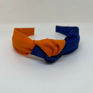 May include: A blue and orange knotted headband. The headband is made of fabric and has a simple design.
