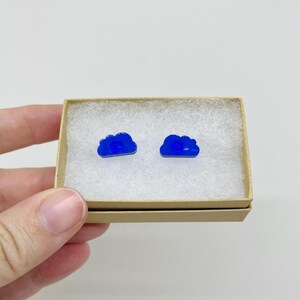 May include: A pair of blue cloud-shaped stud earrings in a small cardboard box.