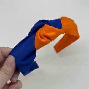 May include: A blue and orange knotted headband. The headband is made of fabric and has a simple design.