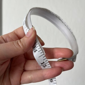 May include: White measuring tape with black markings, showing numbers 13, 14, 15, and 16.