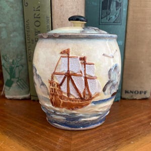 May include: A set of three ceramic mugs with a speckled, matte finish. The mugs are in shades of cream, light brown, and dark brown. Each mug has a simple, minimalist design, perfect for coffee or tea.