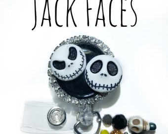 May include: A black and white Jack Skellington face badge reel with a clear plastic badge holder and a charm with black and orange beads and a skull. The text "JACK FACES" is written above the badge reel.