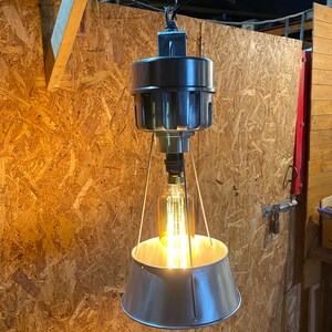 May include: A vintage-style pendant light with a metal shade and a single light bulb. The light is hanging from a chain and has a metal frame.