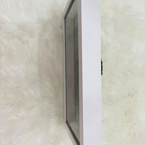 May include: White shadow box with a clear glass front. The shadow box is empty.